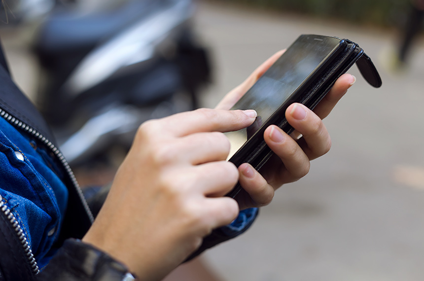 Jovem mulher usando seu celular na rua.